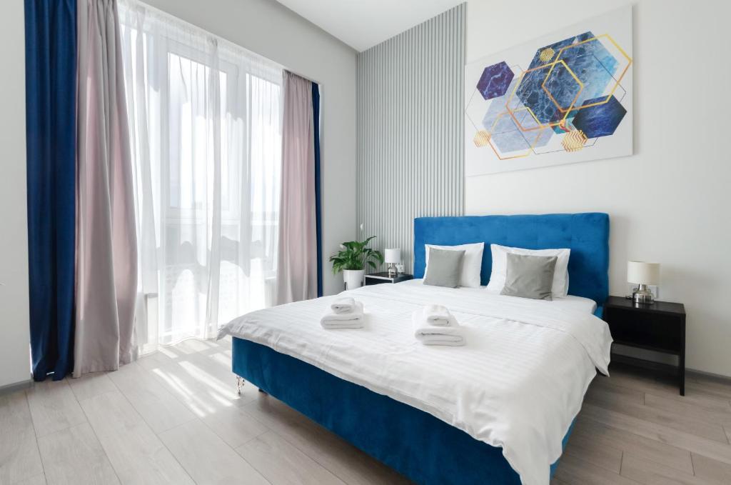 um quarto com uma cama azul e uma grande janela em Smart App near Railway Station Kvartet 3C em Kiev