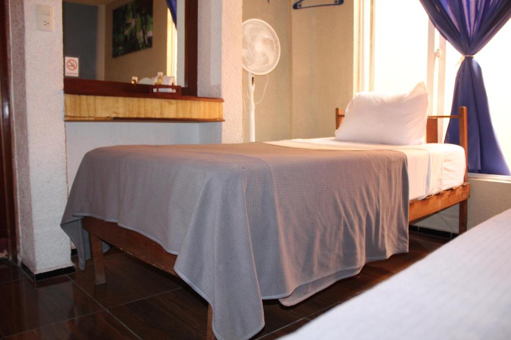 a bedroom with a bed with a blanket on it at Hotel Los Diamantes in Orizaba