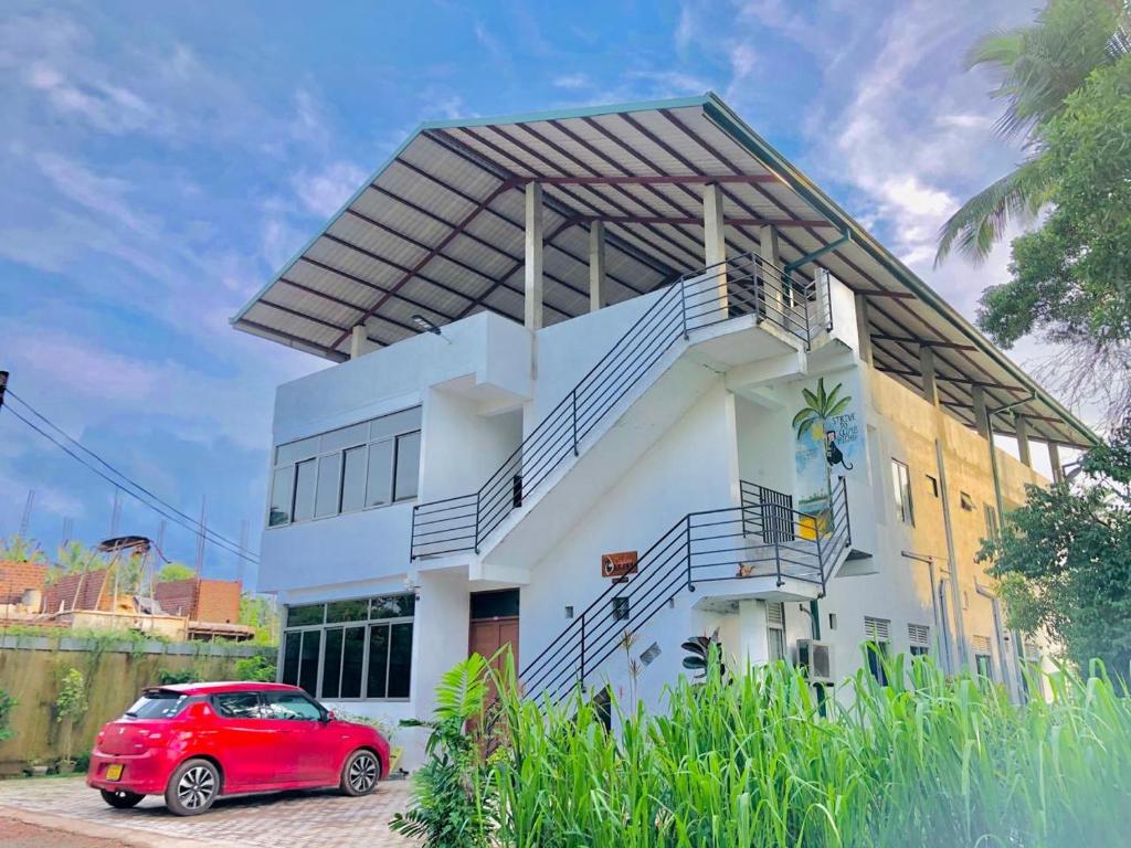 尼甘布的住宿－Ceylon Lodge - Airport Transit Hotel & Hostel，停在房子前面的红色汽车