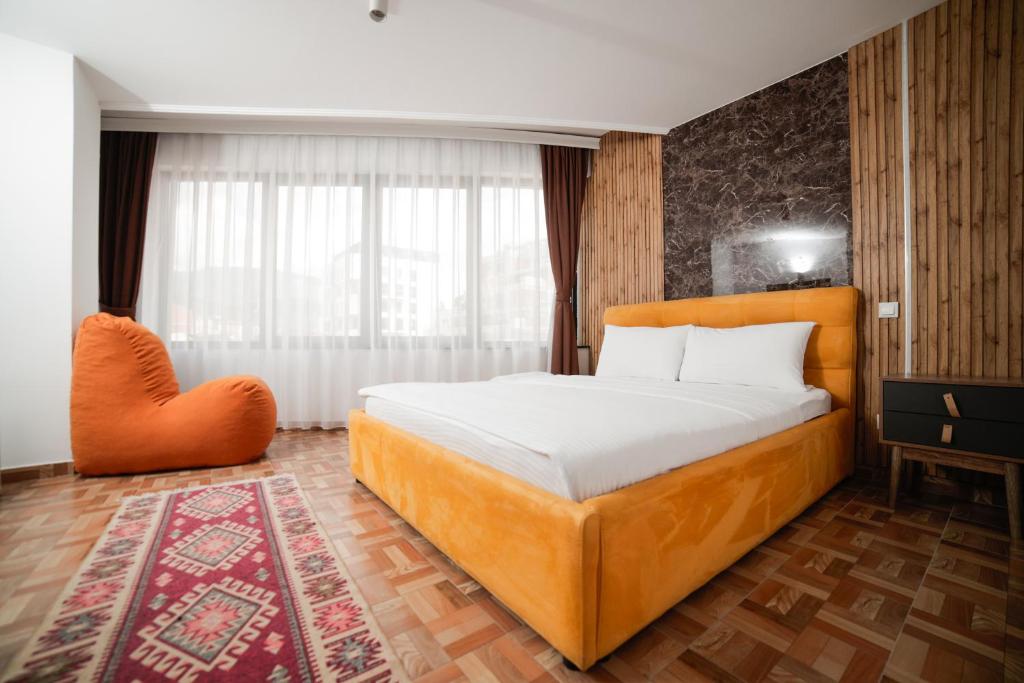 a bedroom with a large bed and an orange chair at Denis Hotel in Prizren