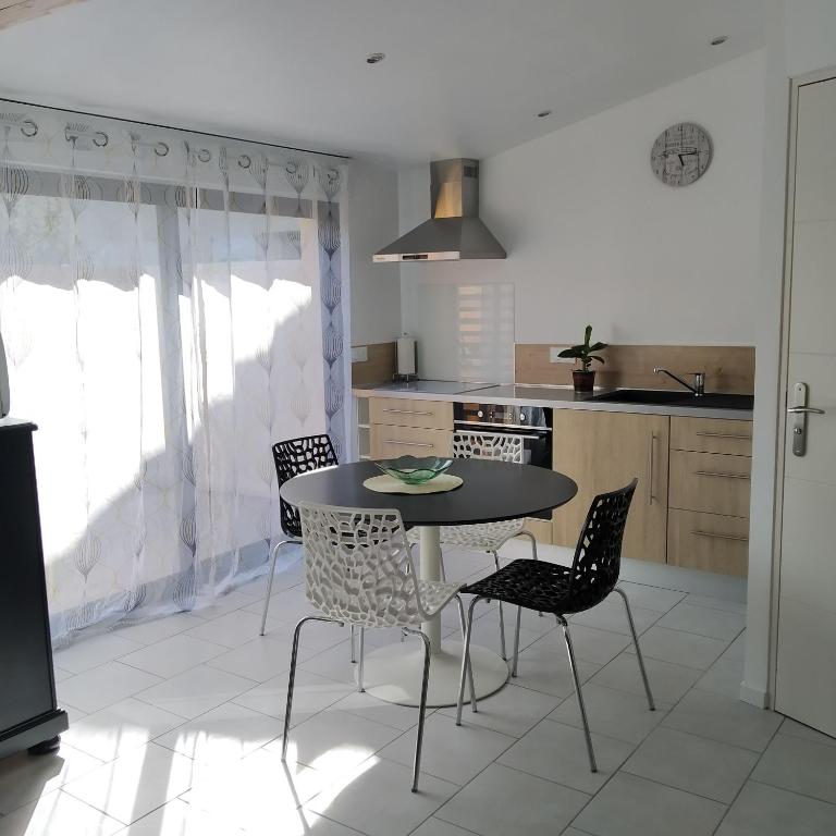 une cuisine avec une table et des chaises dans une pièce dans l'établissement Quatre As - Studio au calme, à Saint-Christophe