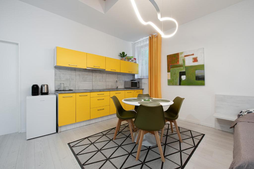 une cuisine avec des armoires jaunes, une table et des chaises dans l'établissement Chillgarden Apartments, à Trenčín