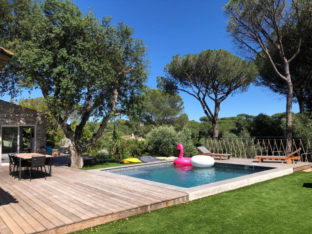 une cour arrière avec une piscine et une terrasse en bois dans l'établissement Villa au grand chêne, à Saint-Raphaël