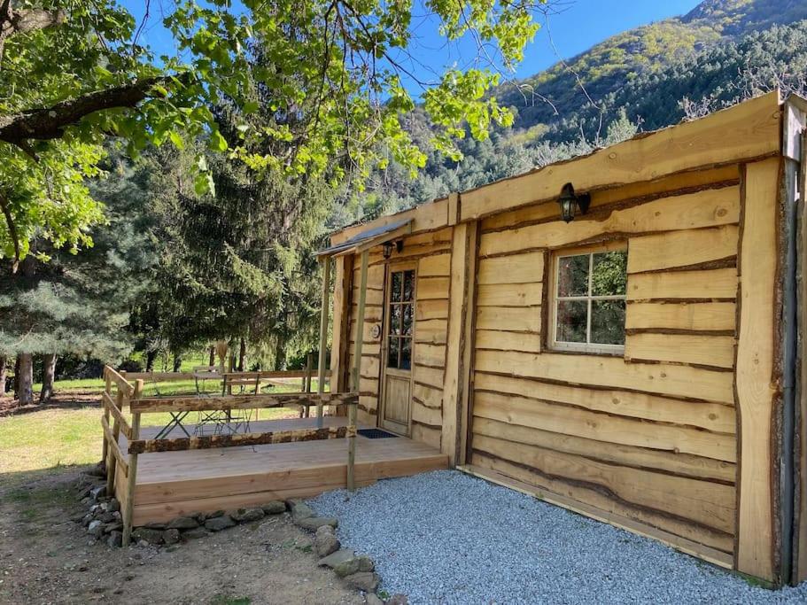 una cabaña de madera con un banco delante en La Cabane trappeur, en Gravières