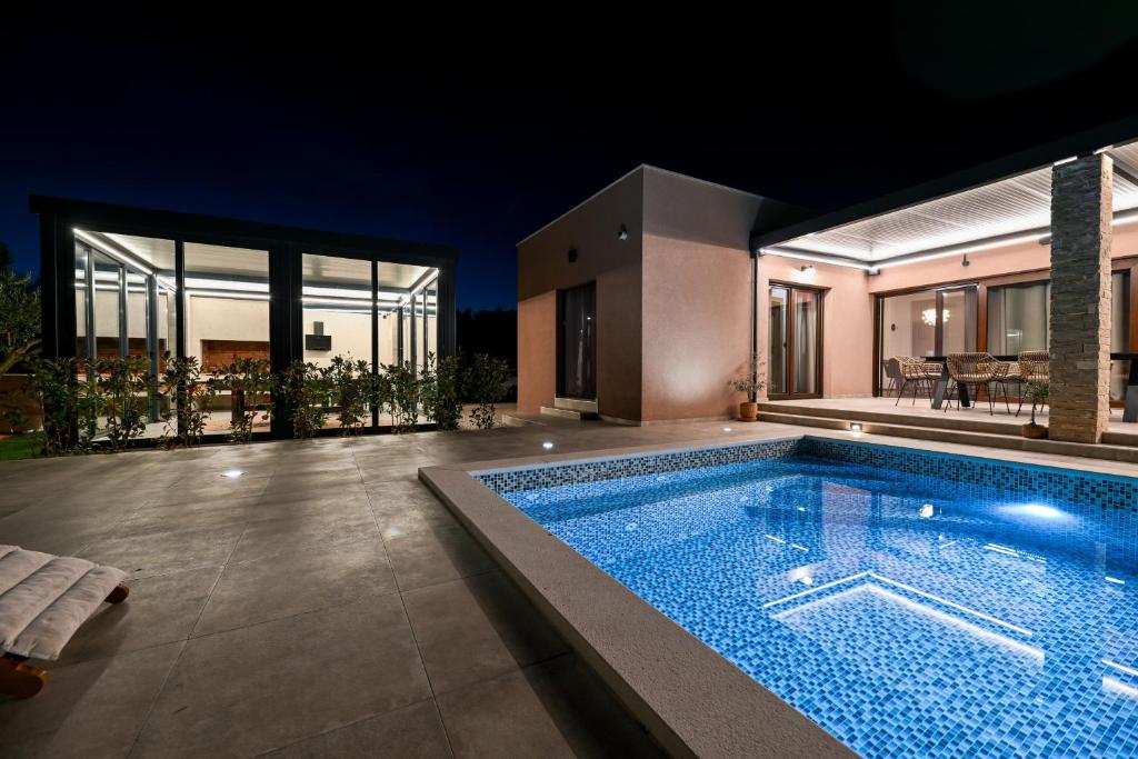 a swimming pool in front of a house at night at Skyfall in Bibinje