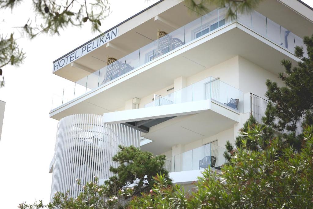 ein Apartmenthaus mit Balkonen und Bäumen in der Unterkunft Hotel Pelikan in Lignano Sabbiadoro