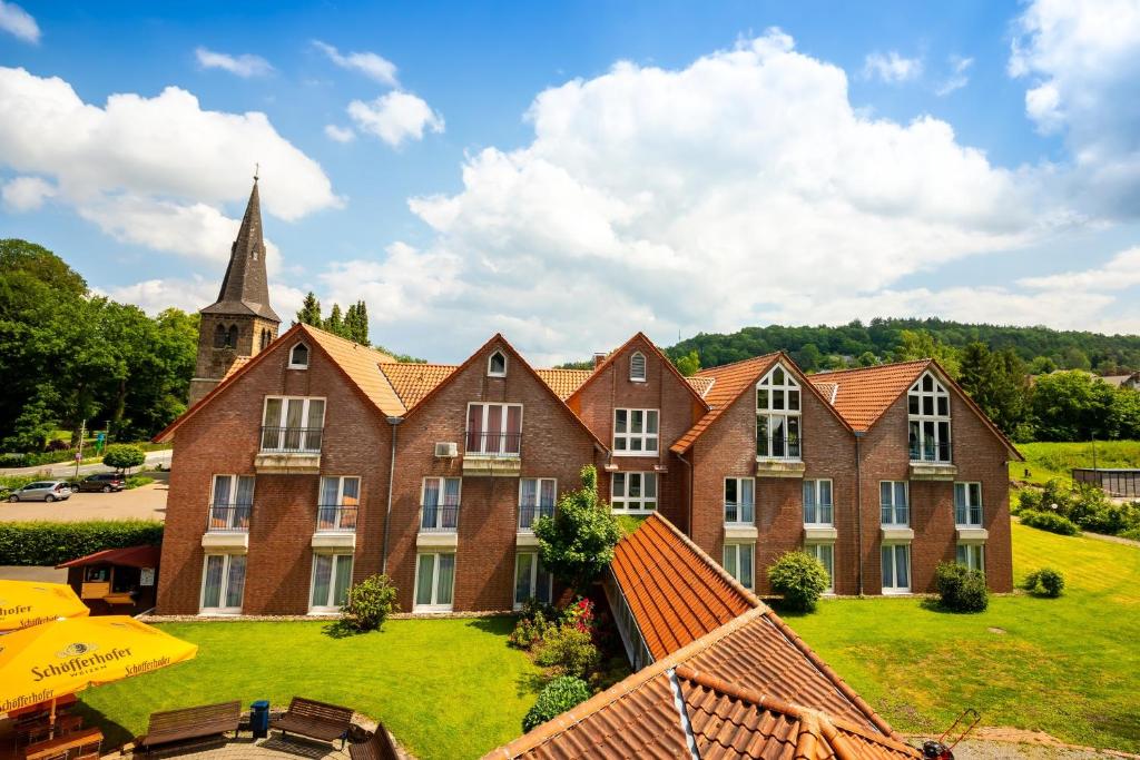 a large brick building with a church with a steeple at Hotel am Park Bad Driburg in Bad Driburg