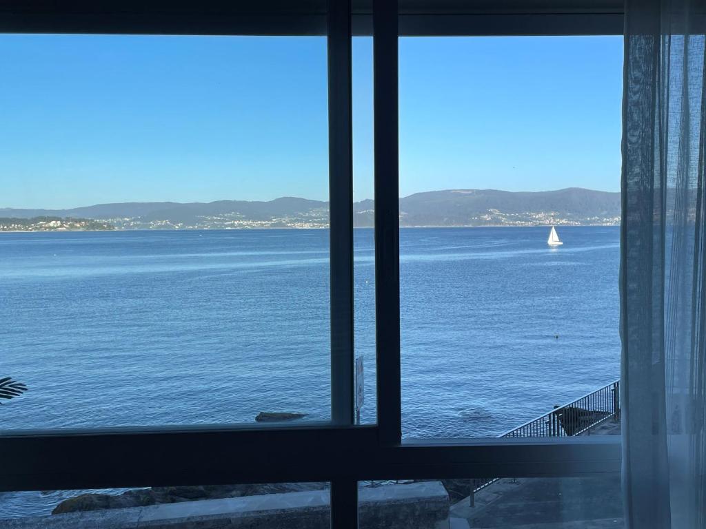 uma vista para o oceano a partir de uma janela em Piso Vacaciones en el mar em Sanxenxo
