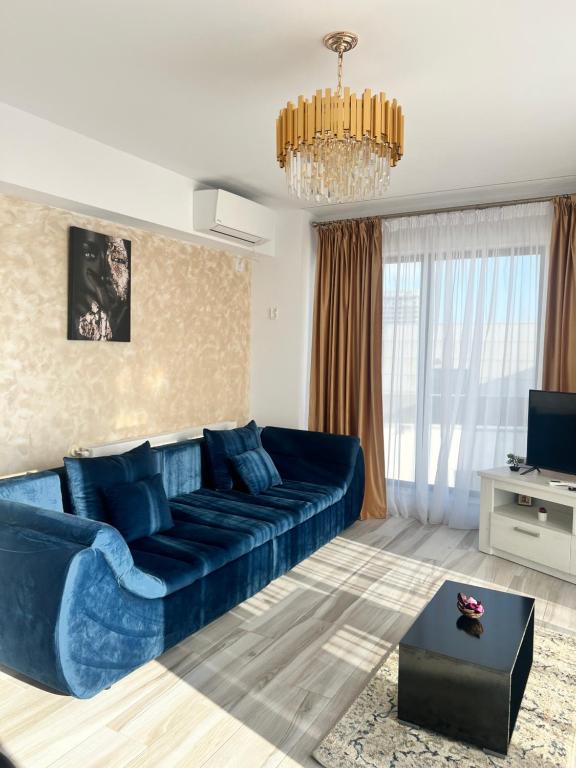 sala de estar con sofá azul y lámpara de araña en Bel Air Mamaia Nord Complex - Apartament Delux en Mamaia