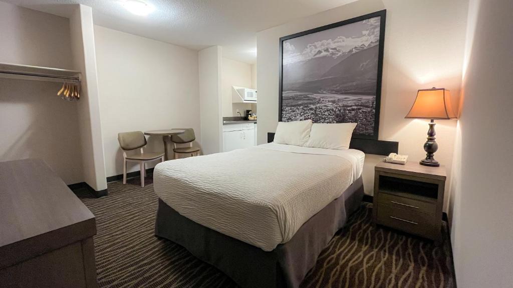 a hotel room with a bed and a kitchen at Super 8 by Wyndham Revelstoke BC in Revelstoke