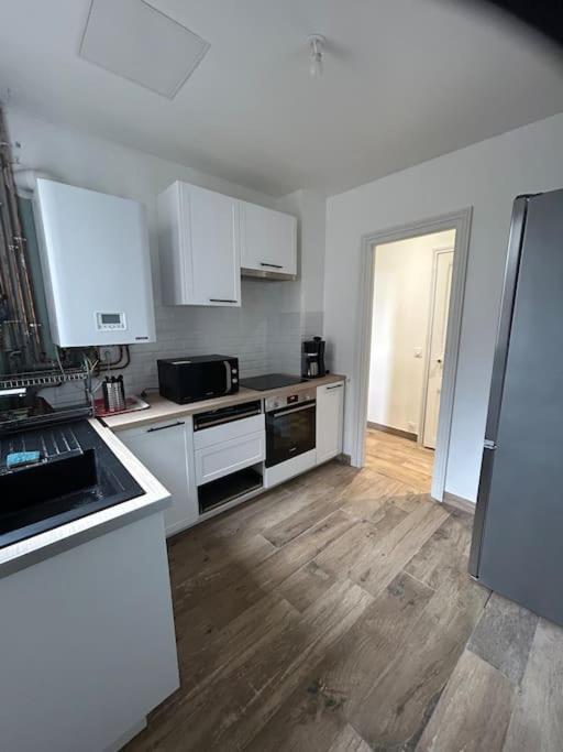a kitchen with white appliances and a wooden floor at Nid douillet proche de Paris in Sarcelles