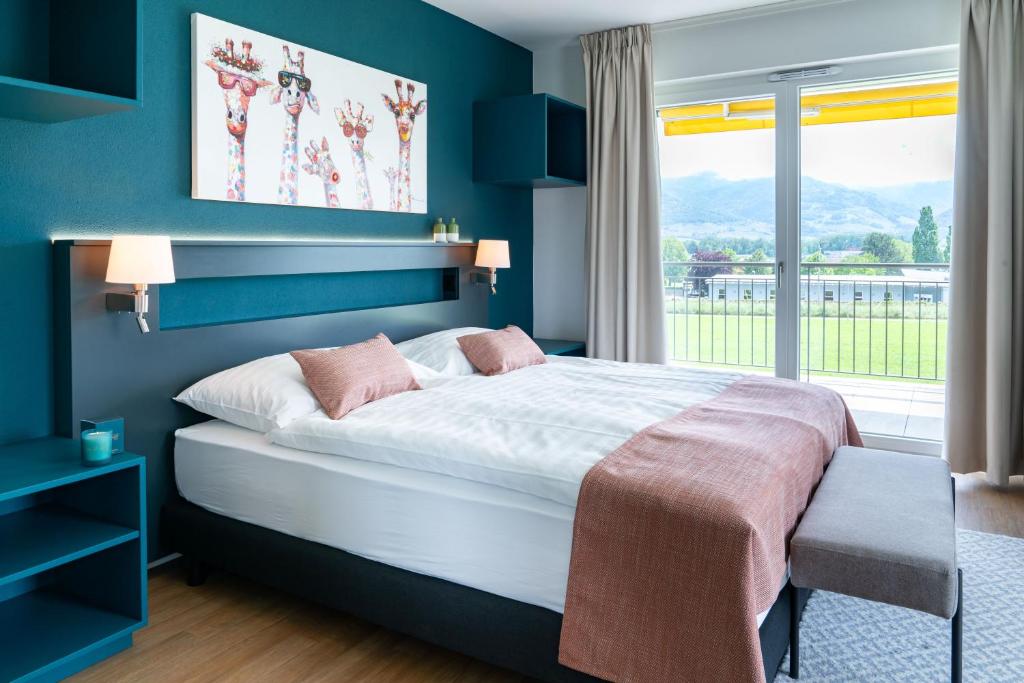 Collombey的住宿－Alp Art Hotel，一间卧室设有一张大床和一个窗户。