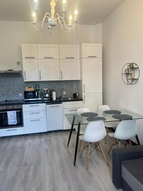 a kitchen with white cabinets and a table and chairs at Apartament Mikolowska 9 in Katowice