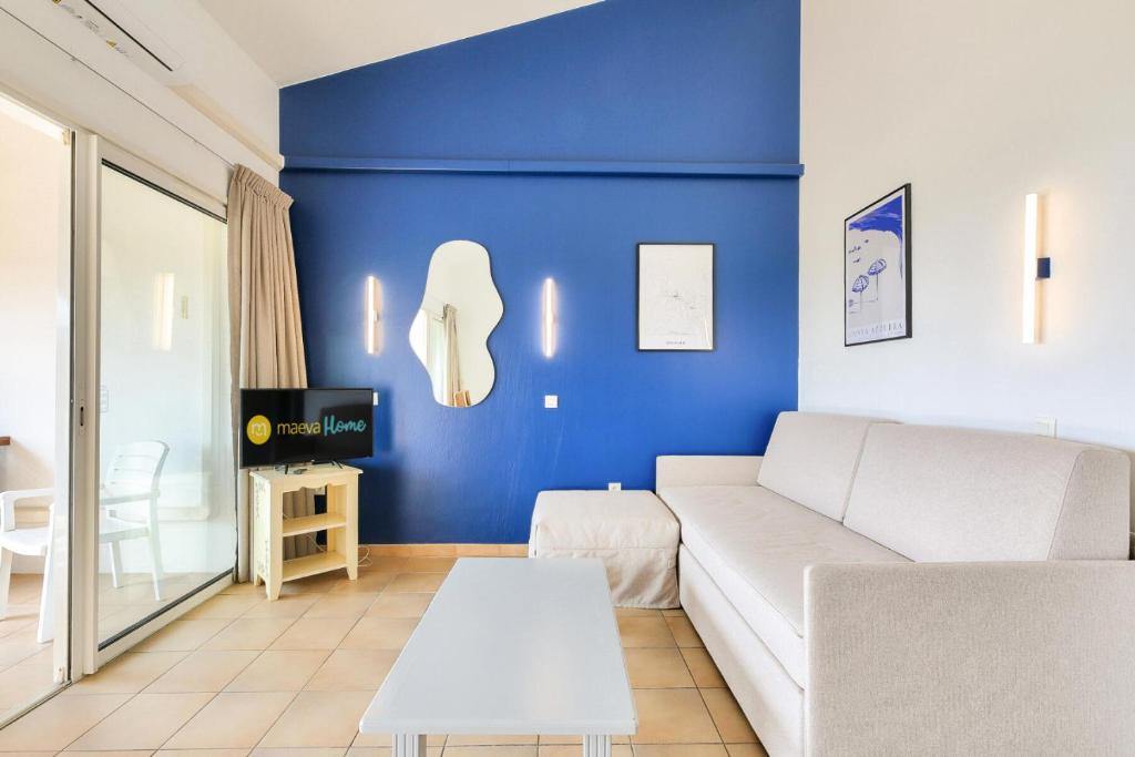 - un salon avec un canapé blanc et un mur bleu dans l'établissement Les Appartements aux Restanques du Golfe de St Tropez - maeva Home - Appartement 2 pièces coin cabine 7 personnes - Sélection - vue Mer MAE-3148, à Grimaud