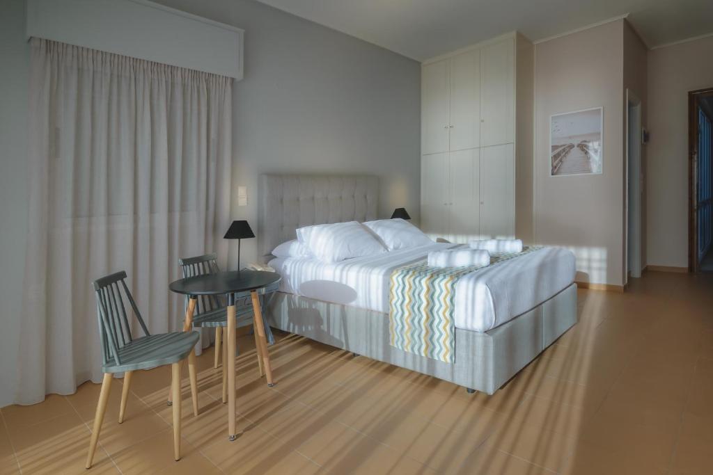 CHIOS HOTEL في Katarráktis: غرفة نوم بسرير وطاولة وكراسي