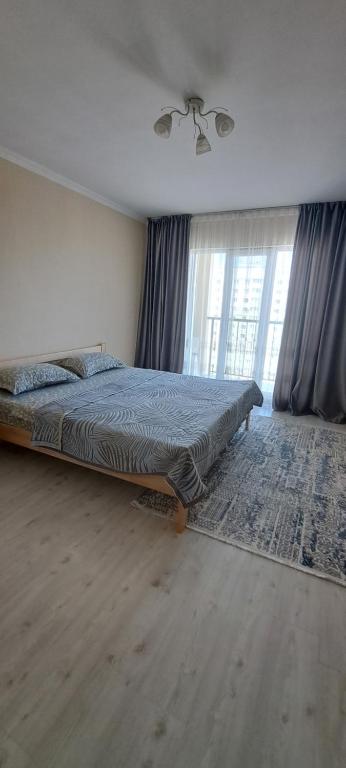 um quarto com uma cama e uma grande janela em 2-комнатная квартира в административном центре. em Türkistan