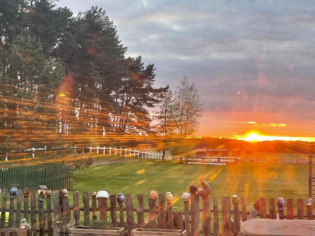 ein Zaun mit Hüten darauf im Sonnenuntergang in der Unterkunft Lansada in Zabór