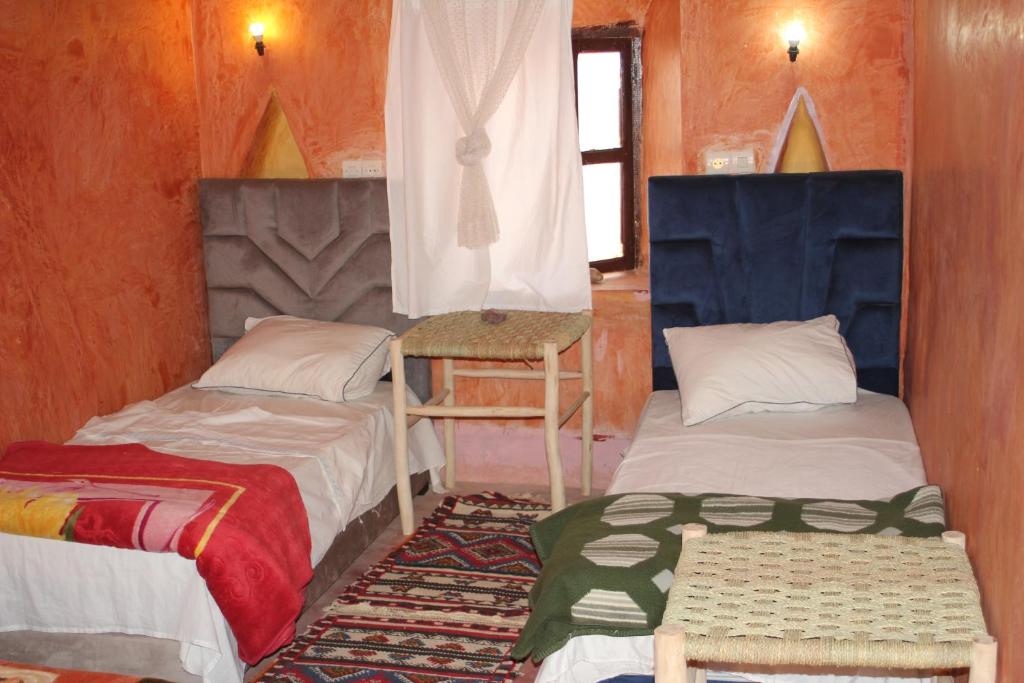 a room with two beds and a chair in it at Dar adiafa dar asalam in Aït Benhaddou