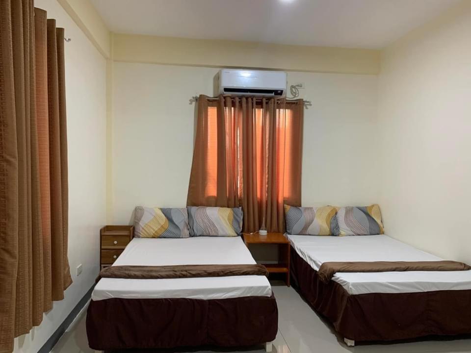 um quarto com duas camas e uma televisão na parede em Llaguno City Inn em General Santos