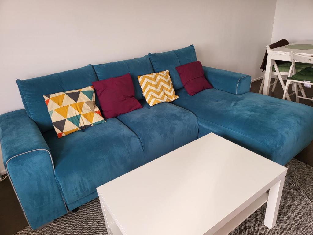 - un canapé bleu avec des oreillers dans le salon dans l'établissement Le clos des lilas - Vitry sur Seine, à Vitry-sur-Seine