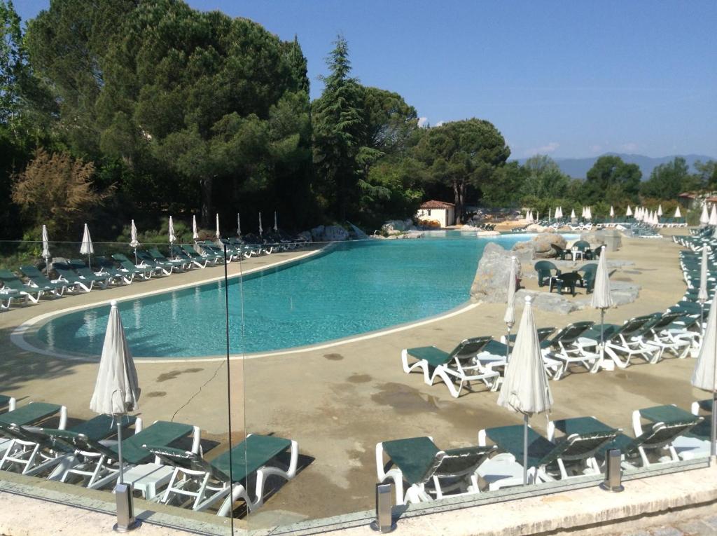 a swimming pool with chairs and umbrellas at Duplex (5pers) dans village vacances en Ardèche in Grospierres