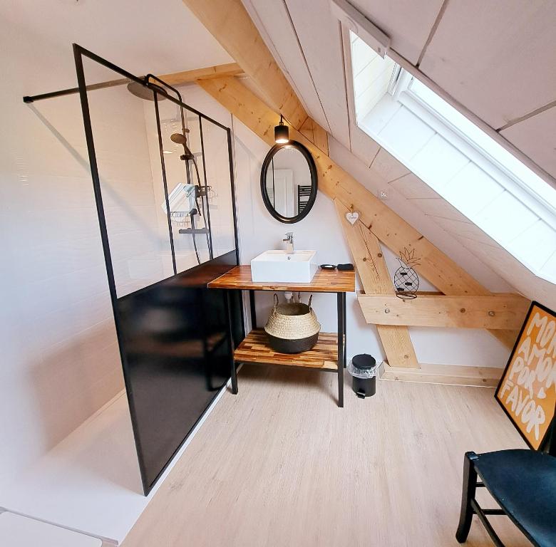 Ein Badezimmer im Dachgeschoss mit Waschbecken und Spiegel in der Unterkunft La maison au bout du chemin in Poey-dʼOloron