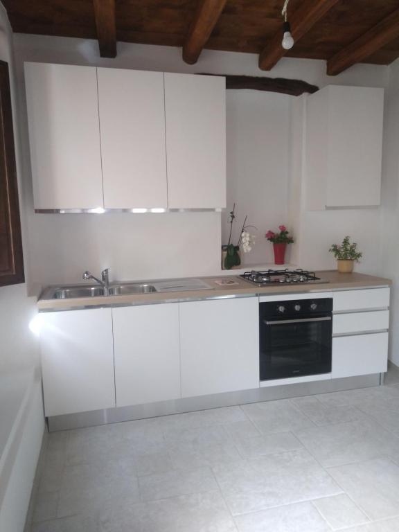 a kitchen with white cabinets and a sink and a stove at Casa di Anna in Baunei