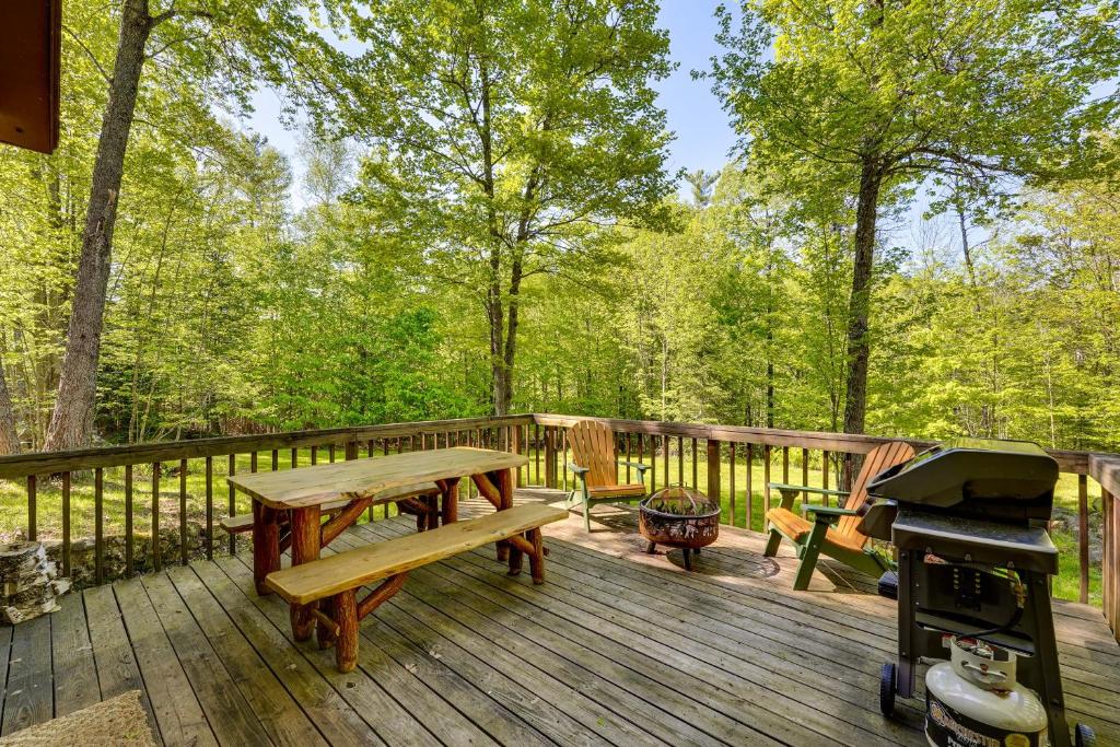 eine Holzterrasse mit einem Picknicktisch und einem Grill in der Unterkunft Saranac Lake Cabin with Deck Pets Welcome! in Saranac Lake