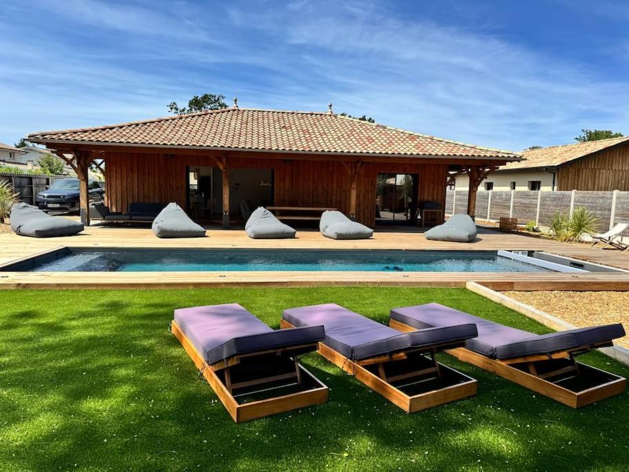 une cour avec deux chaises longues et une piscine dans l'établissement Magnifique Villa Lege Cap Ferret avec piscine, à Lège-Cap-Ferret