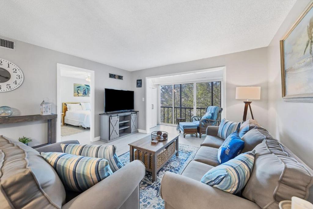 uma sala de estar com um sofá e cadeiras e uma televisão em 2 bed 2 bath centrally located on Siesta Key em Sarasota