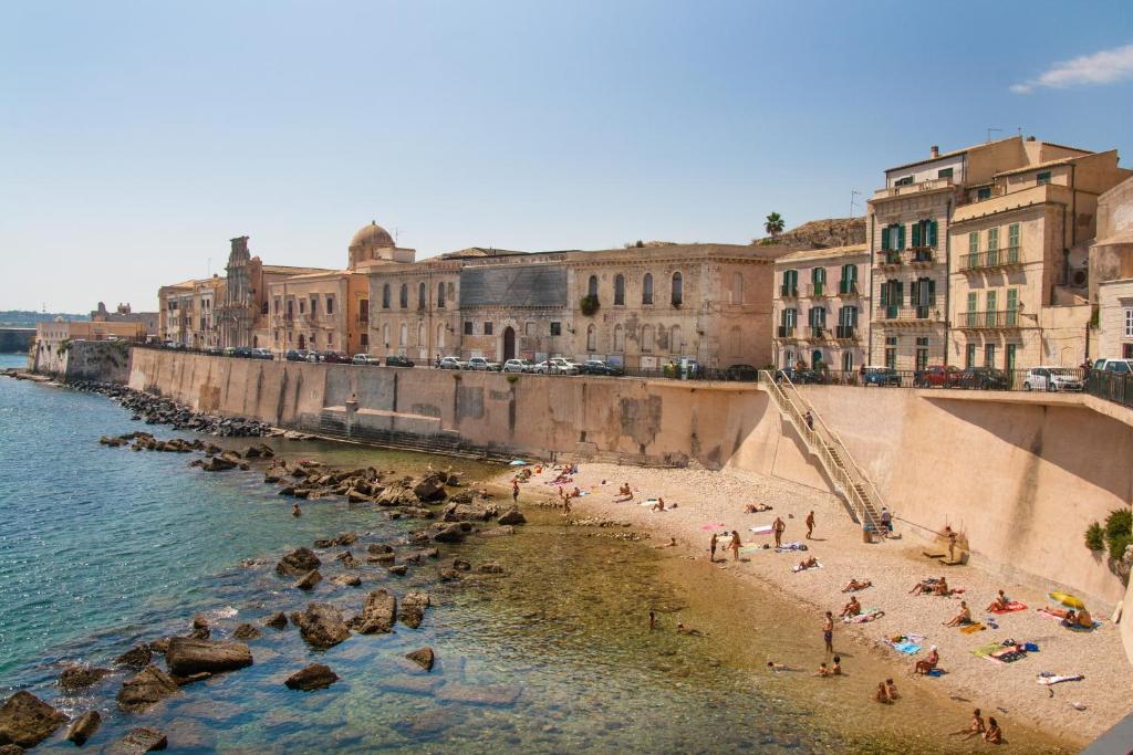 un grupo de personas en una playa cerca del agua en Palazzo Spagna, en Siracusa