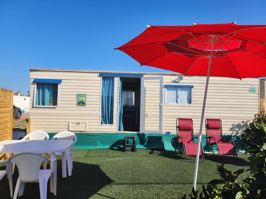 une terrasse avec des chaises et un parasol rouge ainsi qu'une maison dans l'établissement Franceses, à Chiclana de la Frontera