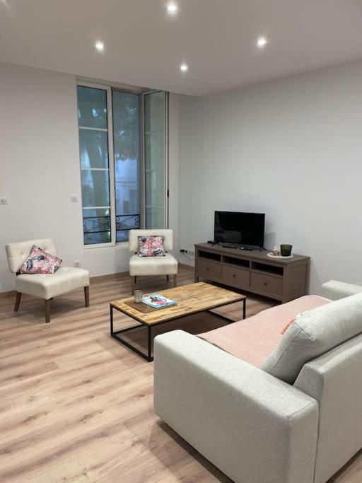 un salon avec un canapé, des chaises et une télévision dans l'établissement Appartement et parking Saintes, à Saintes