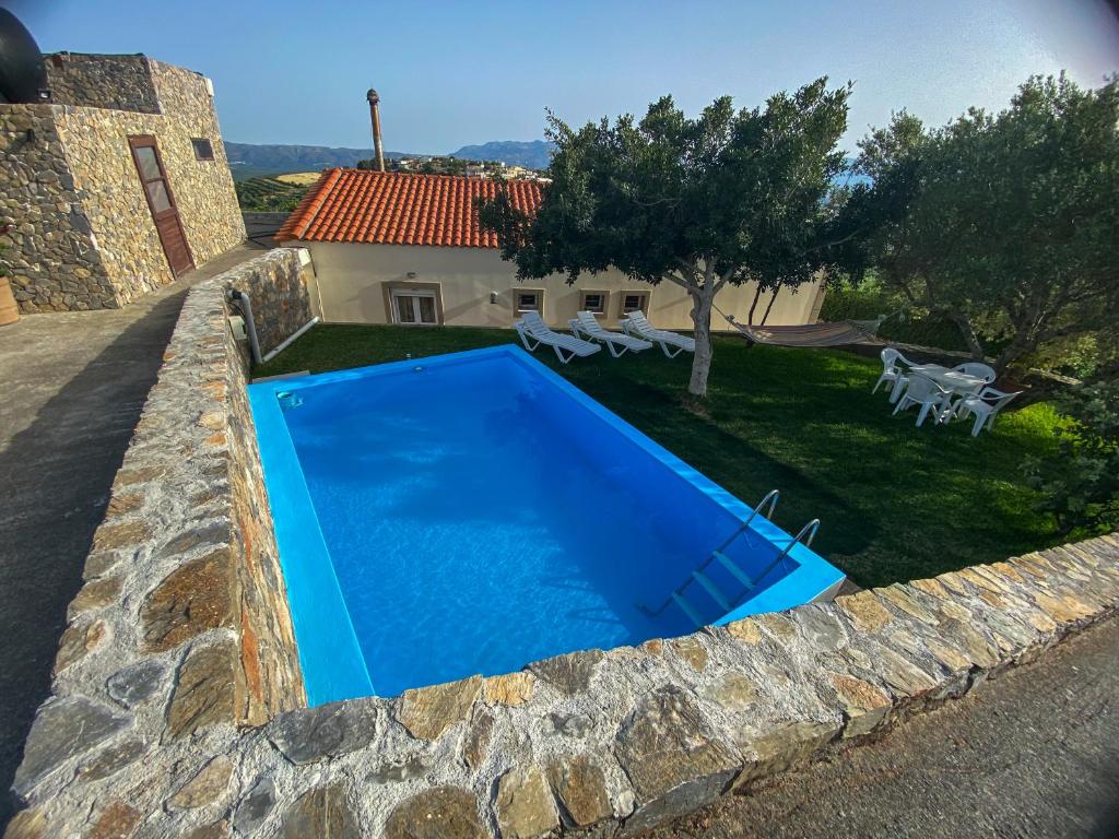 a blue swimming pool in front of a house at Villa Melissa in Ayía Semní