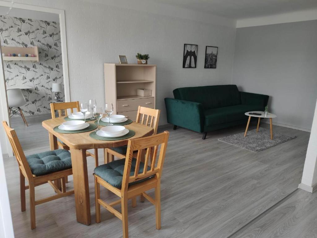 a living room with a table and a green couch at Promenade Apartment in Liepāja