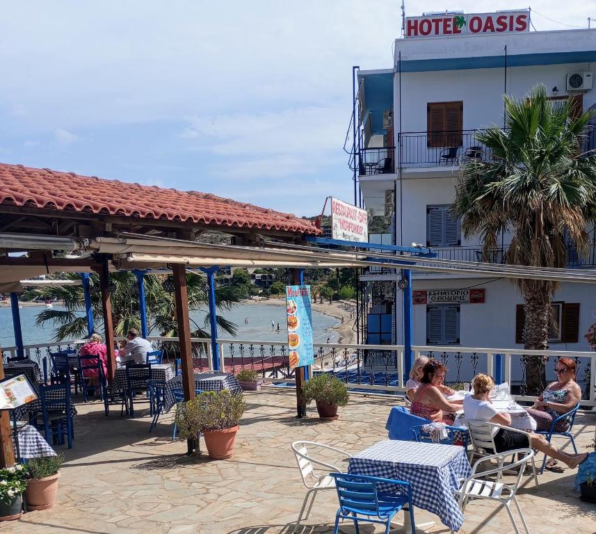 un grupo de personas sentadas en mesas frente a un hotel en Svetlana & Michalis Oasis Hotel en Agia Marina Aegina