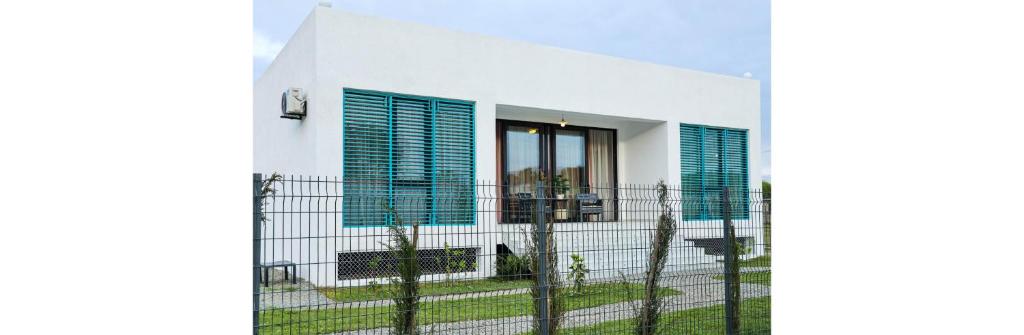 uma casa branca com janelas azuis e uma cerca em Villa Capri-Kaprovani em Shekhvetili