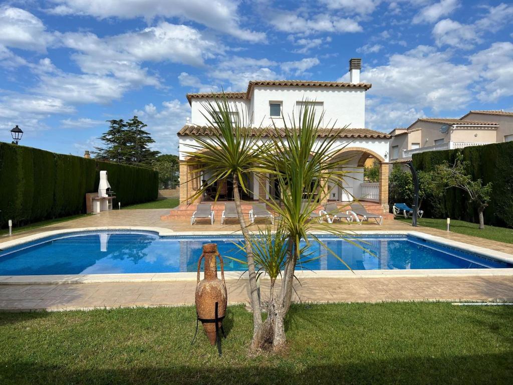 een huis met een zwembad en een palmboom in de tuin bij Belvilla by OYO Nautic Parc 9 in Sant Pere Pescador