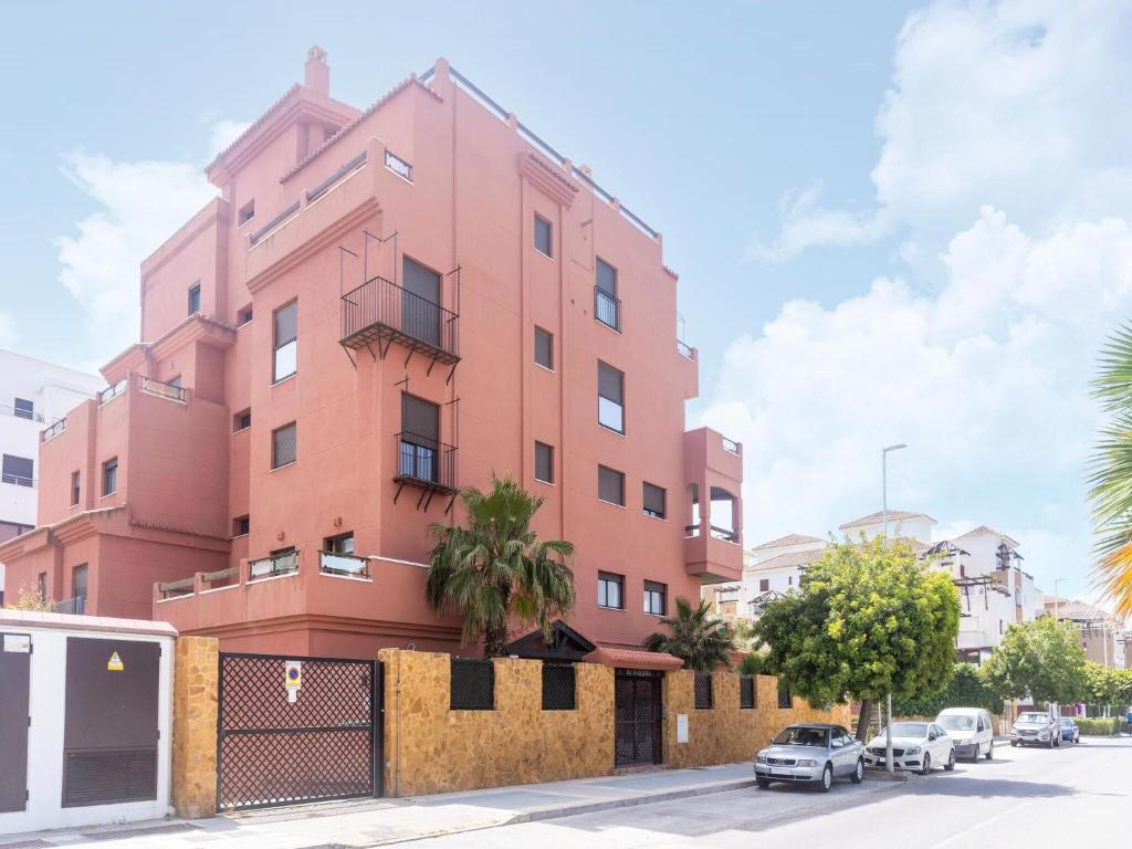 a pink building with cars parked in front of it at Spacious Holiday Home in Motril with 2 Large Terraces in Motril
