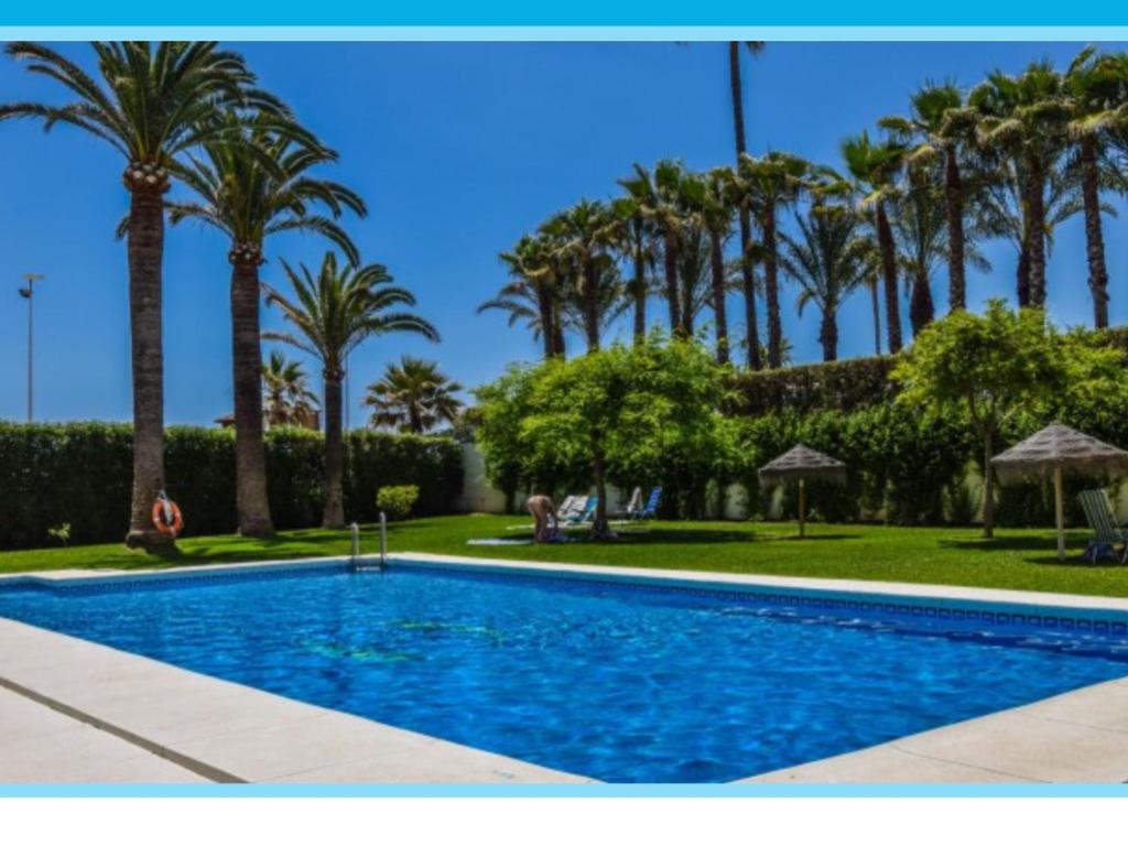 a swimming pool with palm trees in the background at Apartamento TORRESOL NSFA - TORRECILLA, NERJA - studio in Nerja