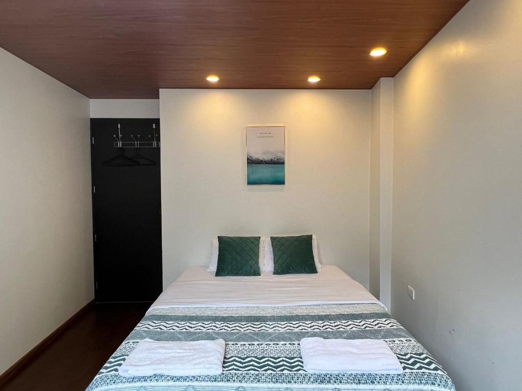 ein kleines Schlafzimmer mit einem Bett mit grünen Kissen in der Unterkunft Pine Hill apartment 1 bedroom 1 bathroom in Baños