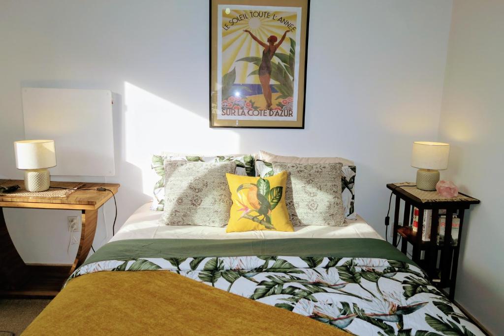 漢密爾頓的住宿－Gully hideaway apartment，一间卧室配有一张带两盏灯的床,墙上挂着一张照片