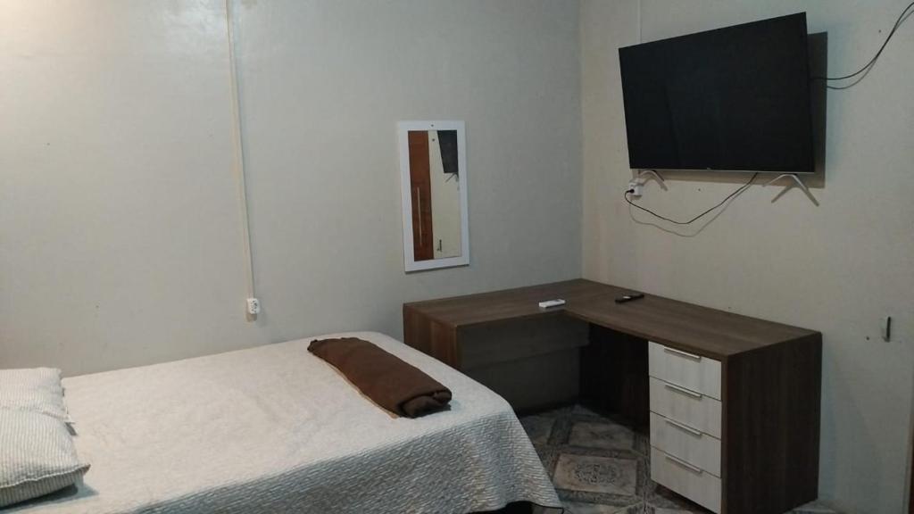 um quarto com uma cama, uma secretária e uma televisão em AP 4 - Apartamento Espaçoso, Confortável e Aconchegante - Pousada Paraíso em Macapá