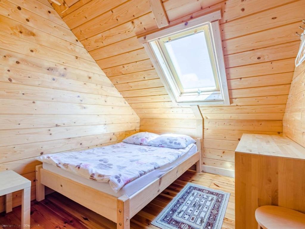 a bed in a wooden room with a window at Domki nad morzem Kąty Rybackie in Kąty Rybackie