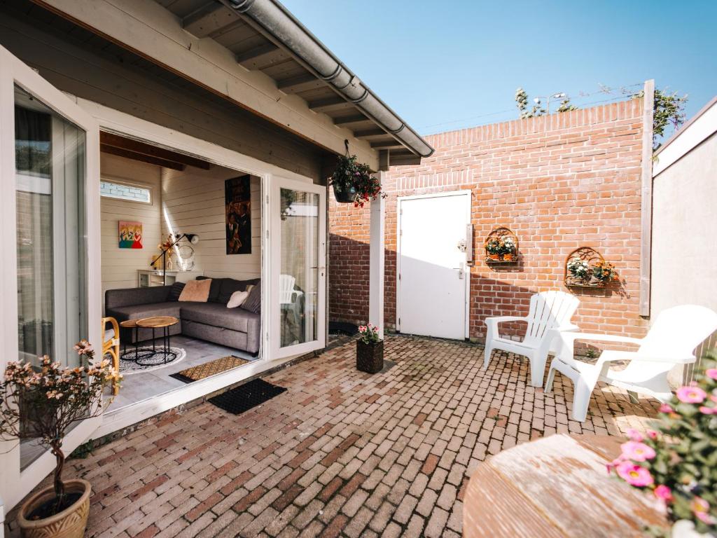 un patio con sofá y sillas en un edificio de ladrillo en Rosa's Cottage, garden and free parking, en Zandvoort