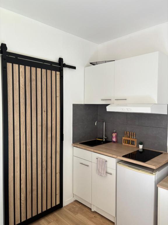 une cuisine avec des armoires blanches et un portail en bois dans l'établissement Lovely studio 600 m Arkéa Arena, à Floirac