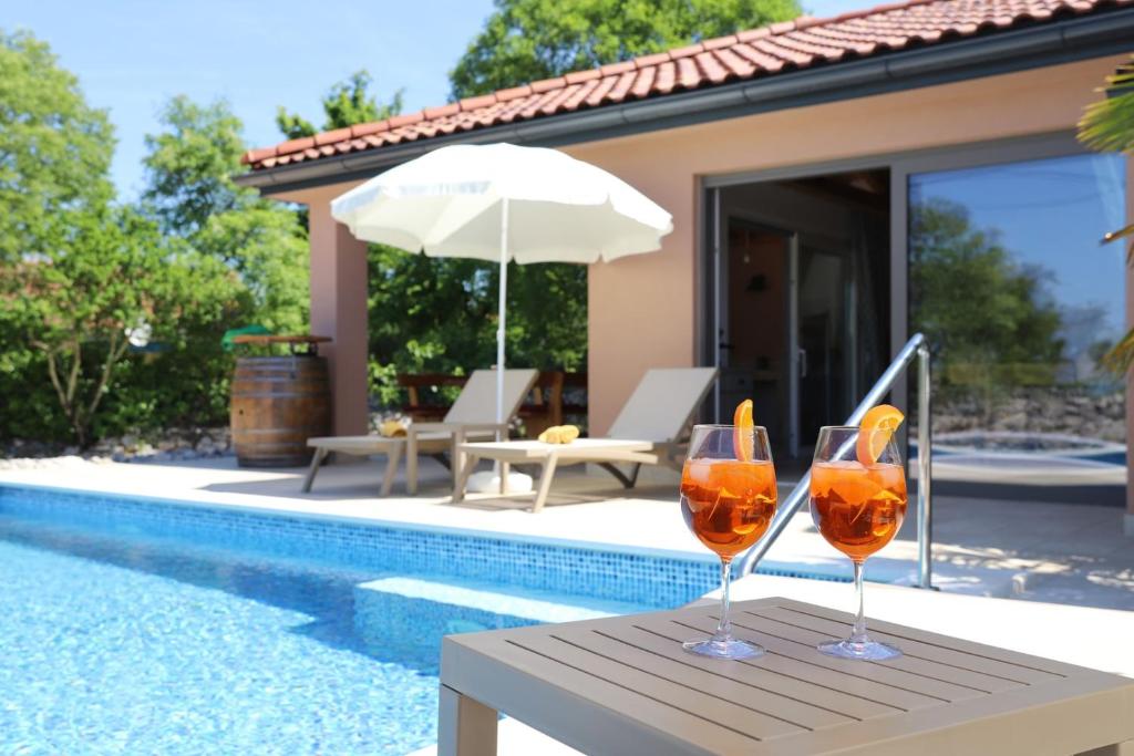 two wine glasses sitting on a table next to a pool at Villa Ulikva in Malinska