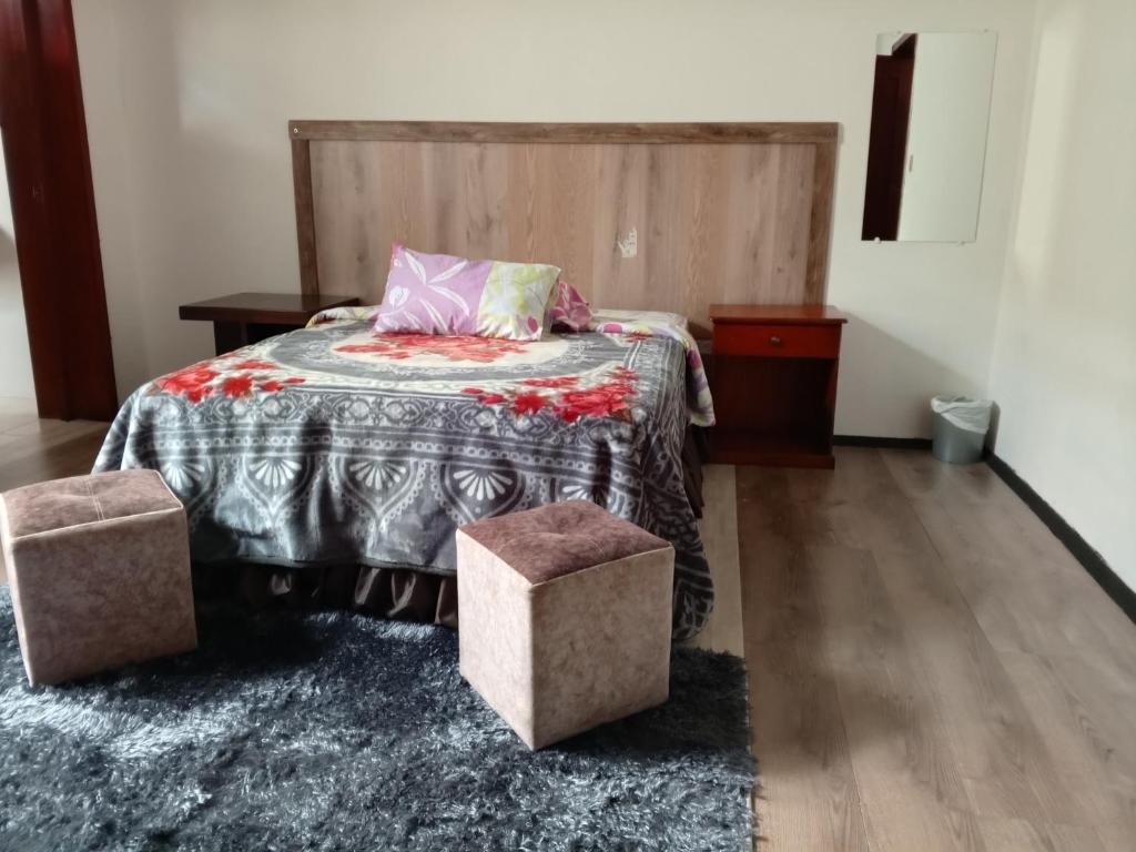 1 dormitorio con 1 cama con cabecero de madera en La Perla Cuencana Hostal en Cuenca