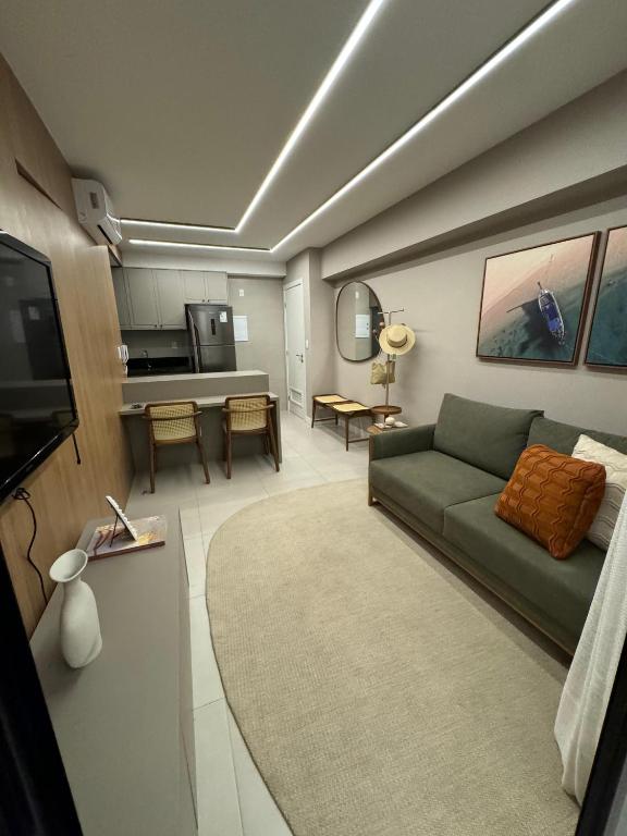a living room with a green couch and a kitchen at Flat Beira-mar - Pepper Village in Salvador