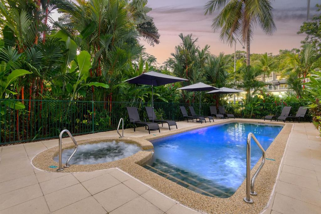 einen Pool mit Stühlen und Sonnenschirmen in einem Resort in der Unterkunft Port Douglas Apartments - Adults Only Oasis in Port Douglas